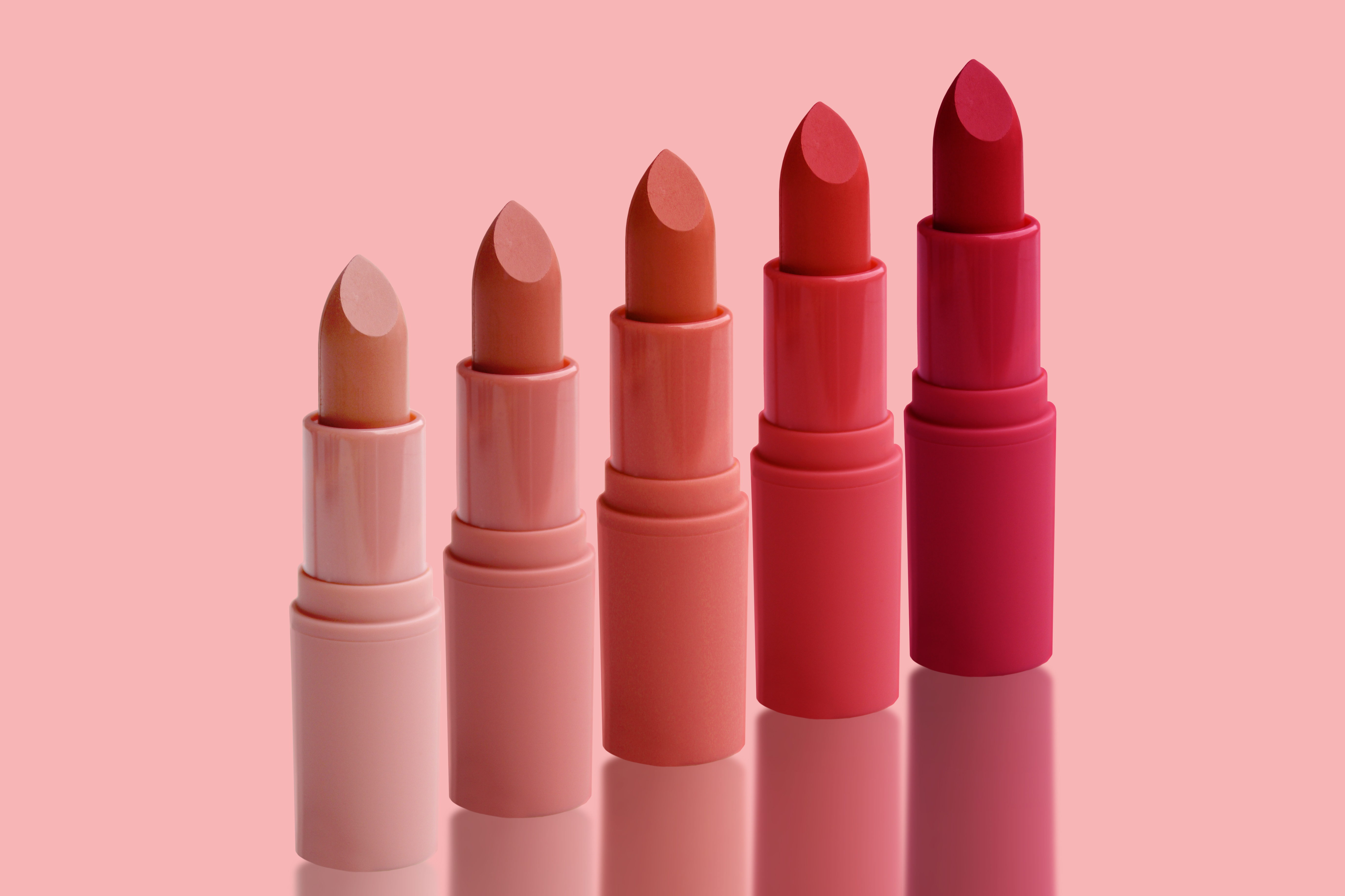 set of matte lipstick on a delicate pink background, red, raspberry, pink, coral, peach color, close-up, the concept of decorative cosmetics